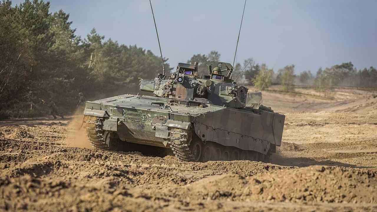 Bojové vozidlo pechoty CV90 počas vojenského cvičenia v pieskovom teréne.