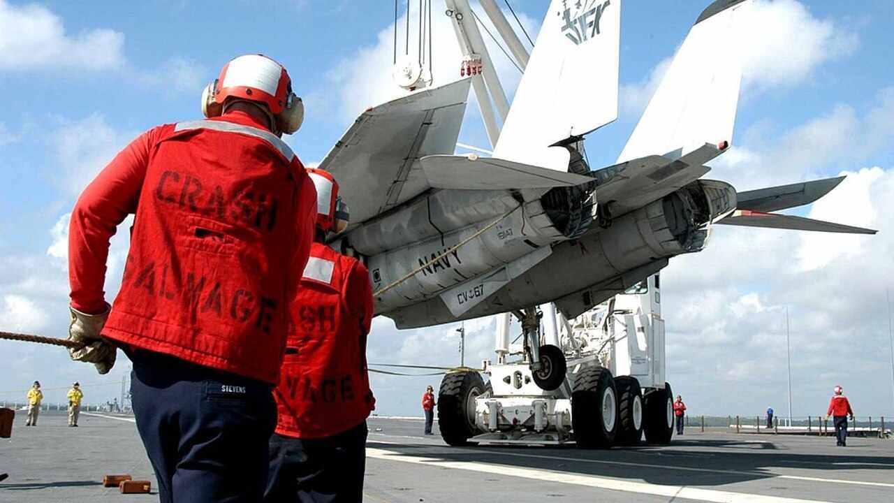 Personál amerického námorníctva manipuluje s lietadlom F-14 Tomcat na palube lietadlovej lode
