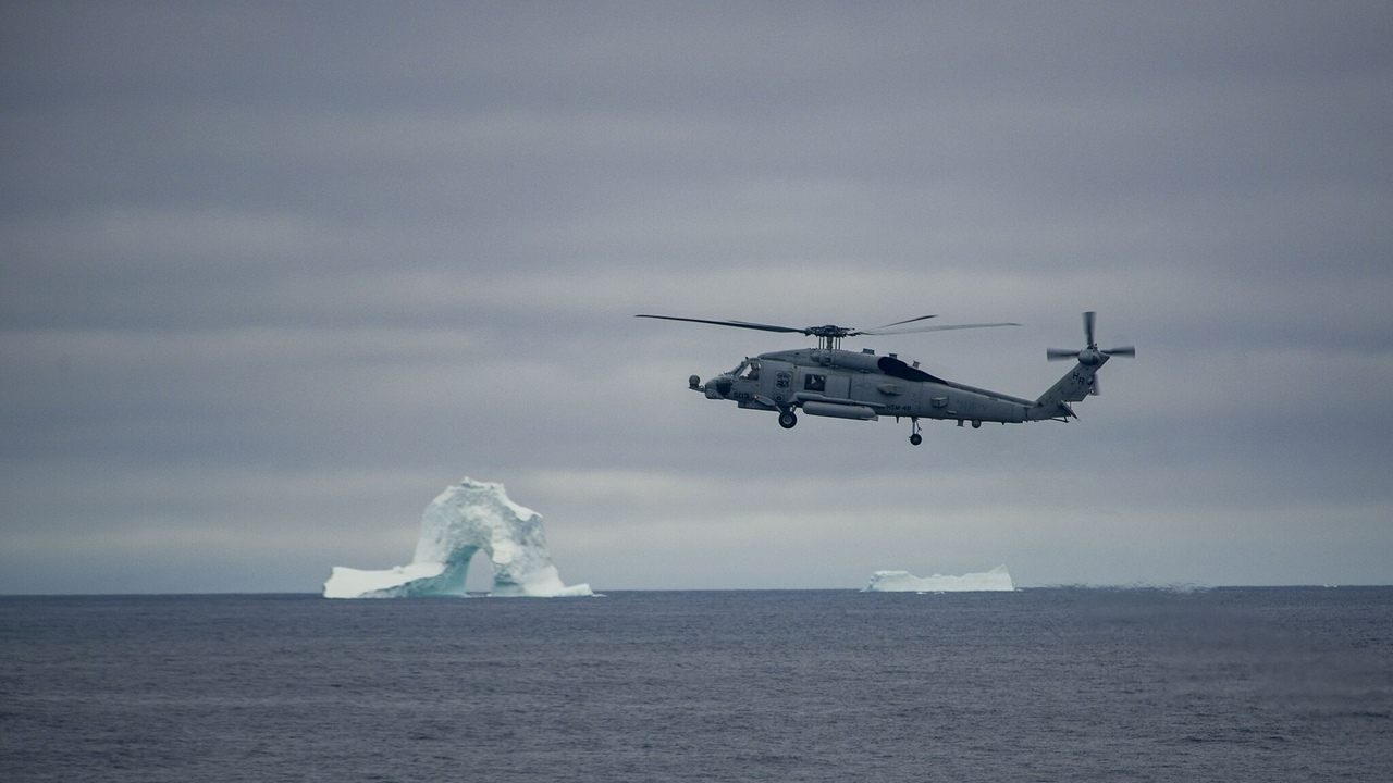 Vrtuľník MH-60R Seahawk amerického námorníctva letí nad morom pri Grónsku počas arktickej operácie.