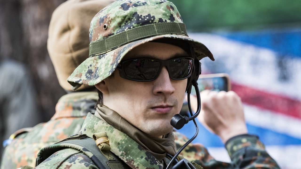 Vojak v maskovacej uniforme používa taktické okuliare a komunikačný headset počas vojenského výcviku