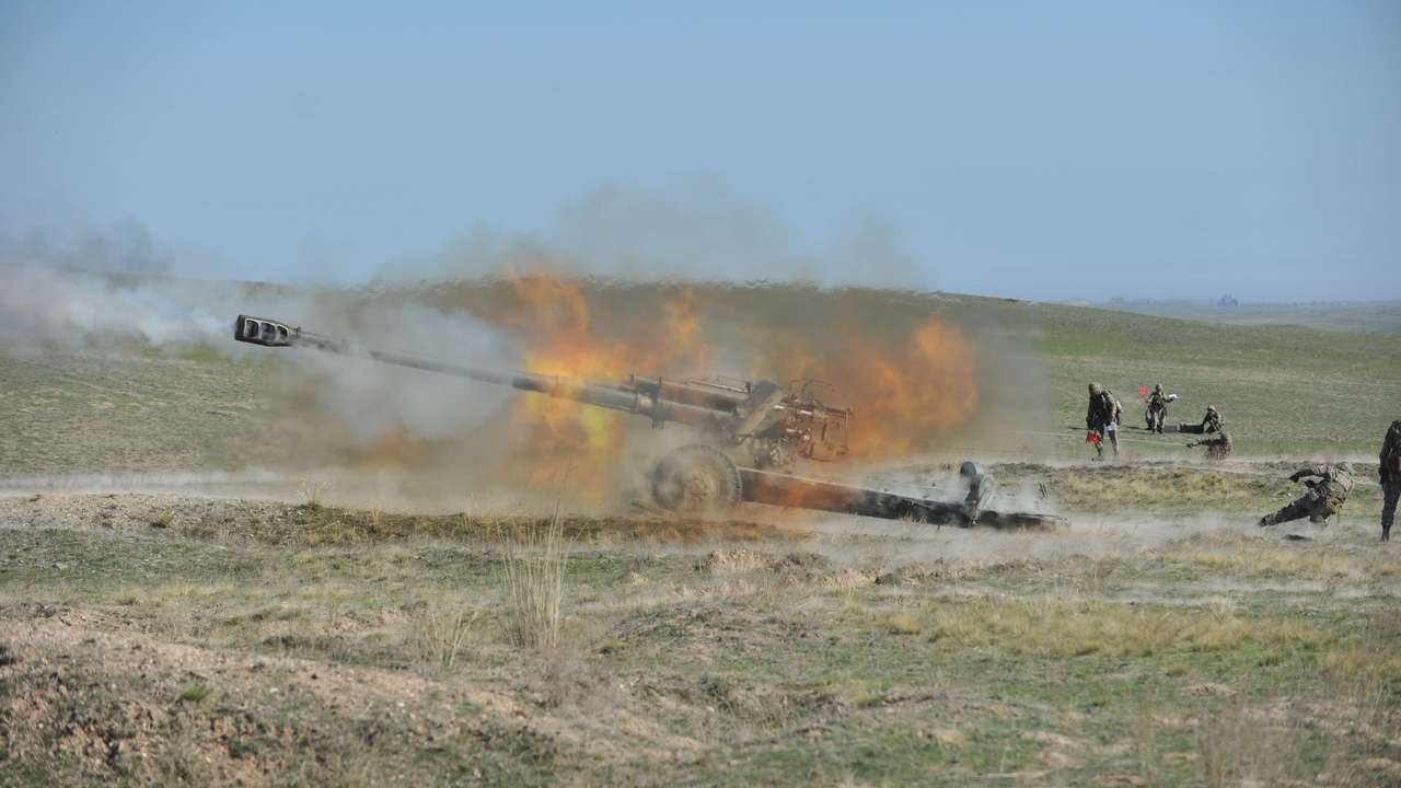 155 mm húfnica pri výstrele, plameň a dym po odpálení delostreleckého granátu na cvičisku