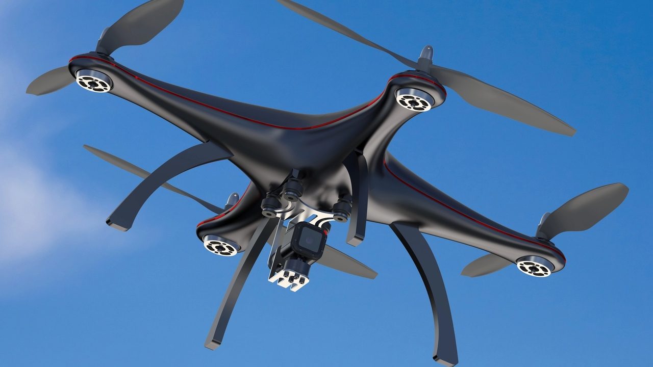 Moderný kvadrokoptérový dron s optickým modulom a kamerou počas letu proti oblohe